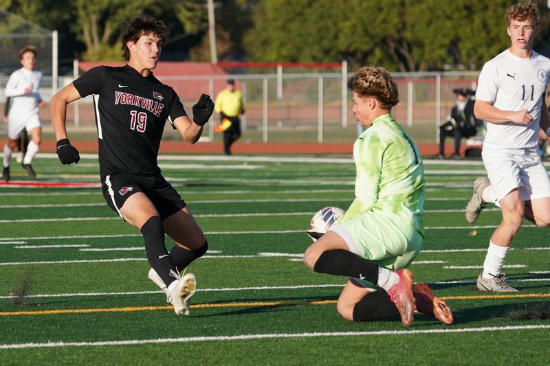 Oswego East's Jack Urbanowski (1) goes on top of the box for a save against Yorkville's Kyle Nadler (19) during a soccer match at Yorkville High School on Tuesday, Oct. 15, 2024.