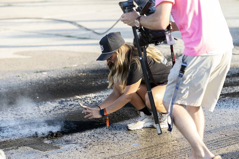 Lexi Upson of Waterford, Mich., snaps some video of smoking rubber after a burnout Thursday, June 19, 2025, in Rock Falls.