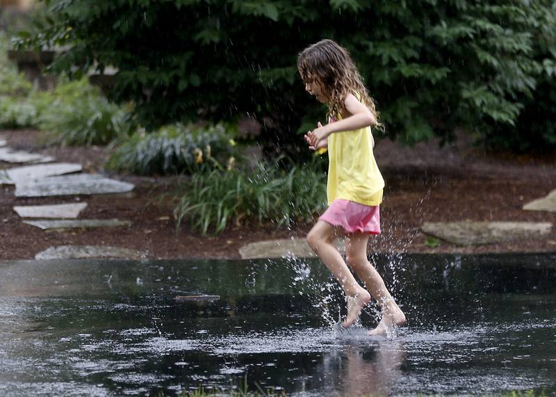 Ella Gleason prefers to play in a puddle than watch the parade on Sunday, July 6, 2024, during Crystal Lake’s annual Independence Day Parade on Dole Avenue in Crystal Lake.