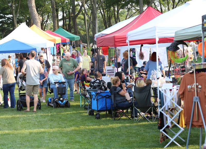 People mingle between booths during the Friday Night Market's event on Friday, Aug. 18, 2023 at Kirby Park in Spring Valley. These well-loved markets, traditionally held on the third Friday of each month, moved from the downtown location in the mini park to the captivating and spacious Kirby Park. Fireworks concluded the event.