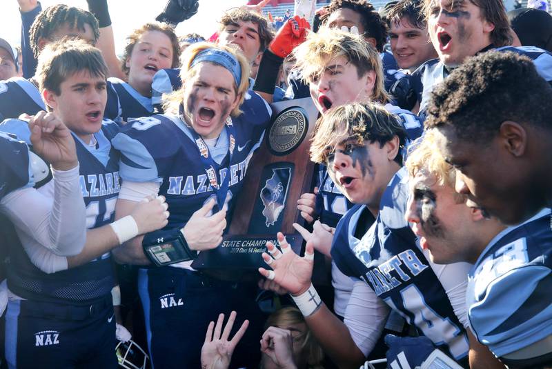 Nazareth celebrates with the trophy Saturday, Nov. 25, 2023, after their IHSA Class 5A state championship win over Joliet Catholic at Hancock Stadium at Illinois State University in Normal.