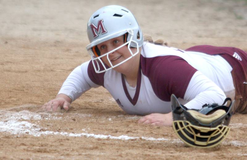 Marengo’s Emily White grins after landing safely at home against Harvard in varsity softball at Marengo Thursday.