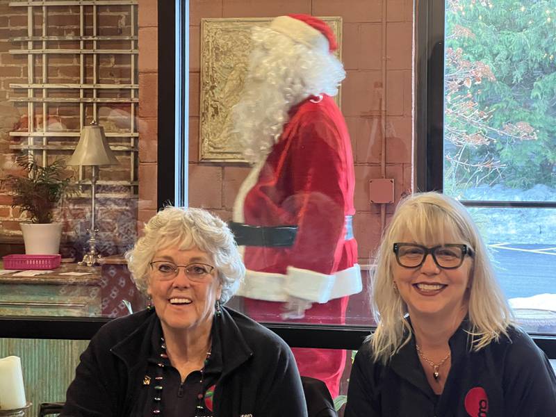 Goodfellows of DeKalb and Sycamore president Sandy Lancaster sits next to Nancy Mangan on Dec. 24, 2025, at Blumen Gardens in Sycamore, as Brick VanDerSnick walks behind them while dressed as Santa Claus.
