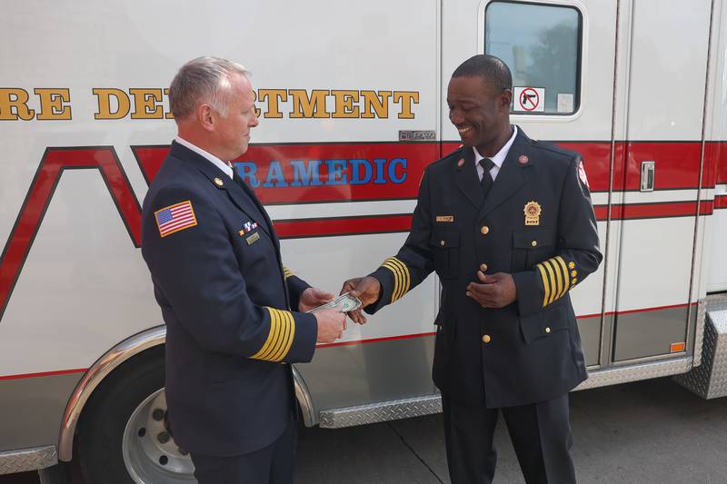 Ford Heights Deputy Fire Chief Nicolas Drake, left, pays Joliet Fire Chief Jeff Casey two dollars for the ambulance that was donated to the Ford Heights Fire Department at the Joliet Fire Department on East Clinton Street
on Tuesday, Oct. 22, 2024.