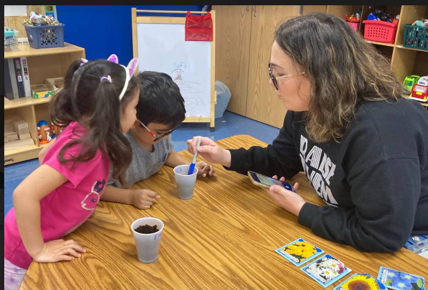 Jennamarie Lopez, a teacher at Minooka School District 201's multilingual program, works with her pre-K students, Elliot and Elany on planting their own flowers as part of their early childhood unit on spring.