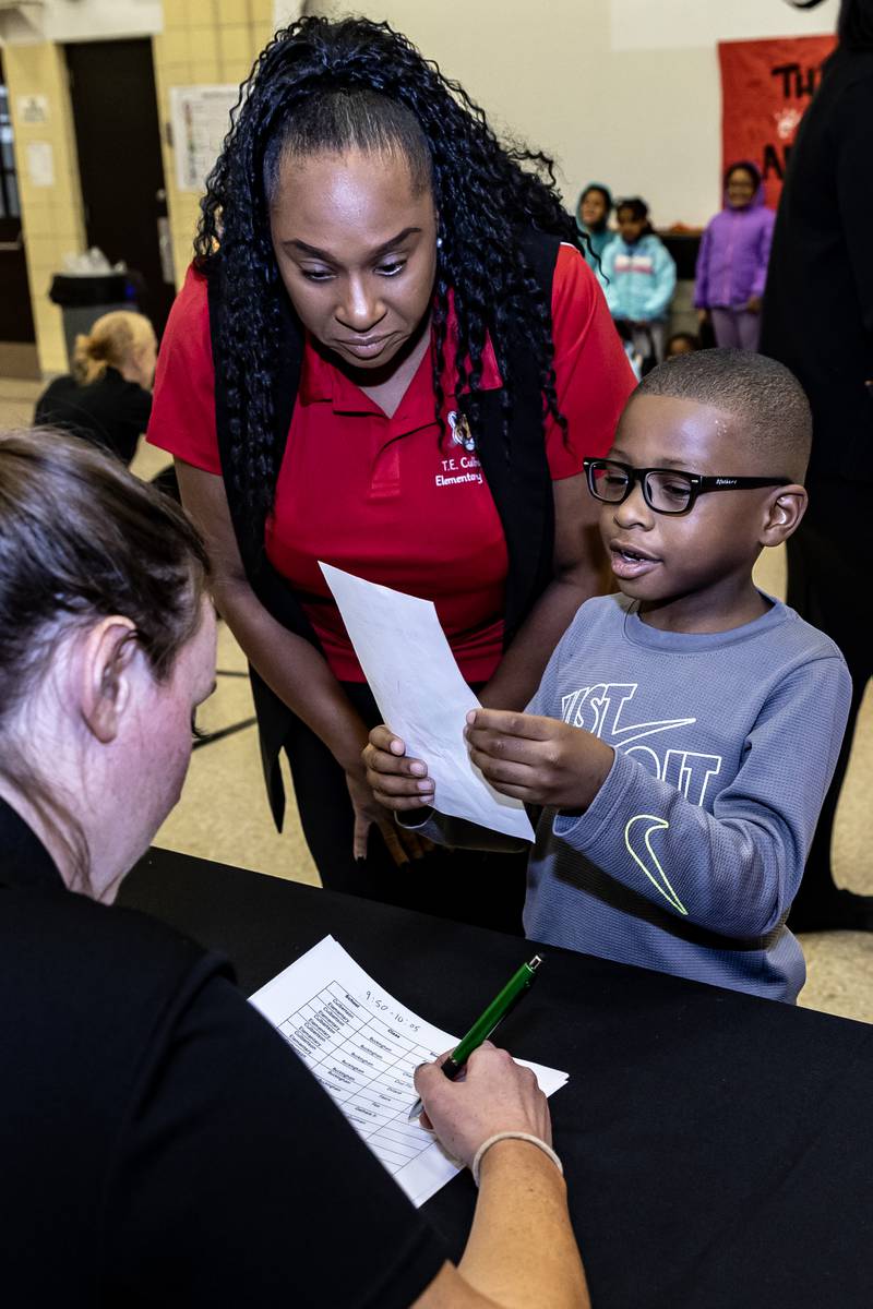 Assistant Principal Ashanti Howard helps first grader Brandon Gathers check-in with Nicor representative Mary Kate Naughton during the winter coat event hosted by Nicor Gas, in collaboration with Operation Warm, at T. E. Culbertson Elementary School on Nov. 7, 2025.