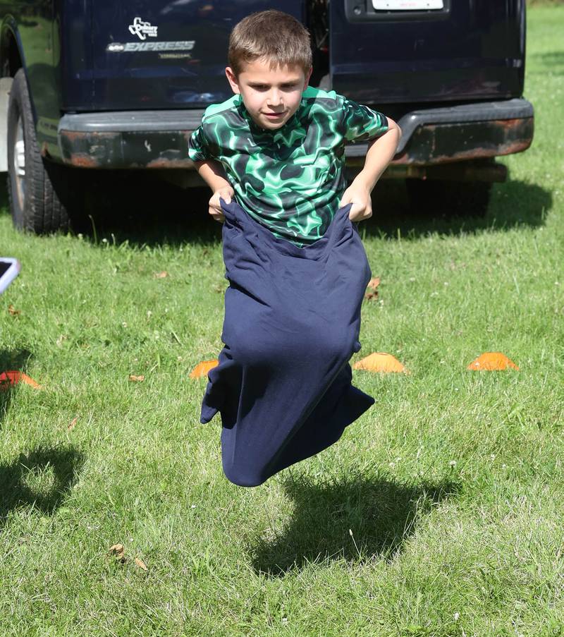 Aaron Martinez, 9, from Cortland, does the sack race at one of the booths during the Family Fun Fest Wednesday, July 17, 2024, at Hopkins Park in DeKalb.