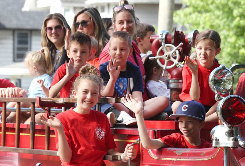 Family members of DeKalb firefighters wave from a truck Monday, May 29, 2023, during the DeKalb Memorial Day parade.