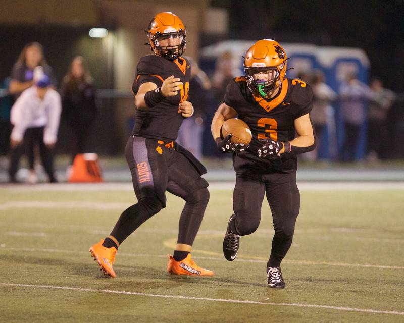 Wheaton Warrenville South's Justin Miller (16) hands the ball off to Owen Yorke (3) against St. Charles North on Friday, Oct. 10, 2025 in Wheaton.