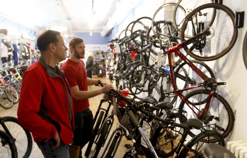 Rich Toepper, of Woodstock, talks with Avant Cycle shop manager Kyle Busse while shopping at the bike shop during the Lighting of the Square event Friday, Nov. 25, 2022, in Woodstock. The annual event featured brass music, caroling, free doughnuts and cider, food trucks, festive selfie stations and shopping.