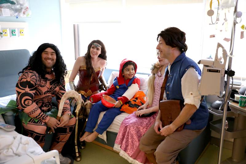 Daylon Terry, 7, of DeKalb gets a visit from (from left) Michael Nishimura as Maui, Abbo Rago as Wonder Woman, Jen Watson as Rapunzel and Scott Eckelberry as Flynn during a Halloween visit to the pediatric intensive care unit of Northwestern Central DuPage Hospital in Winfield on Tuesday, Oct. 31, 2023.