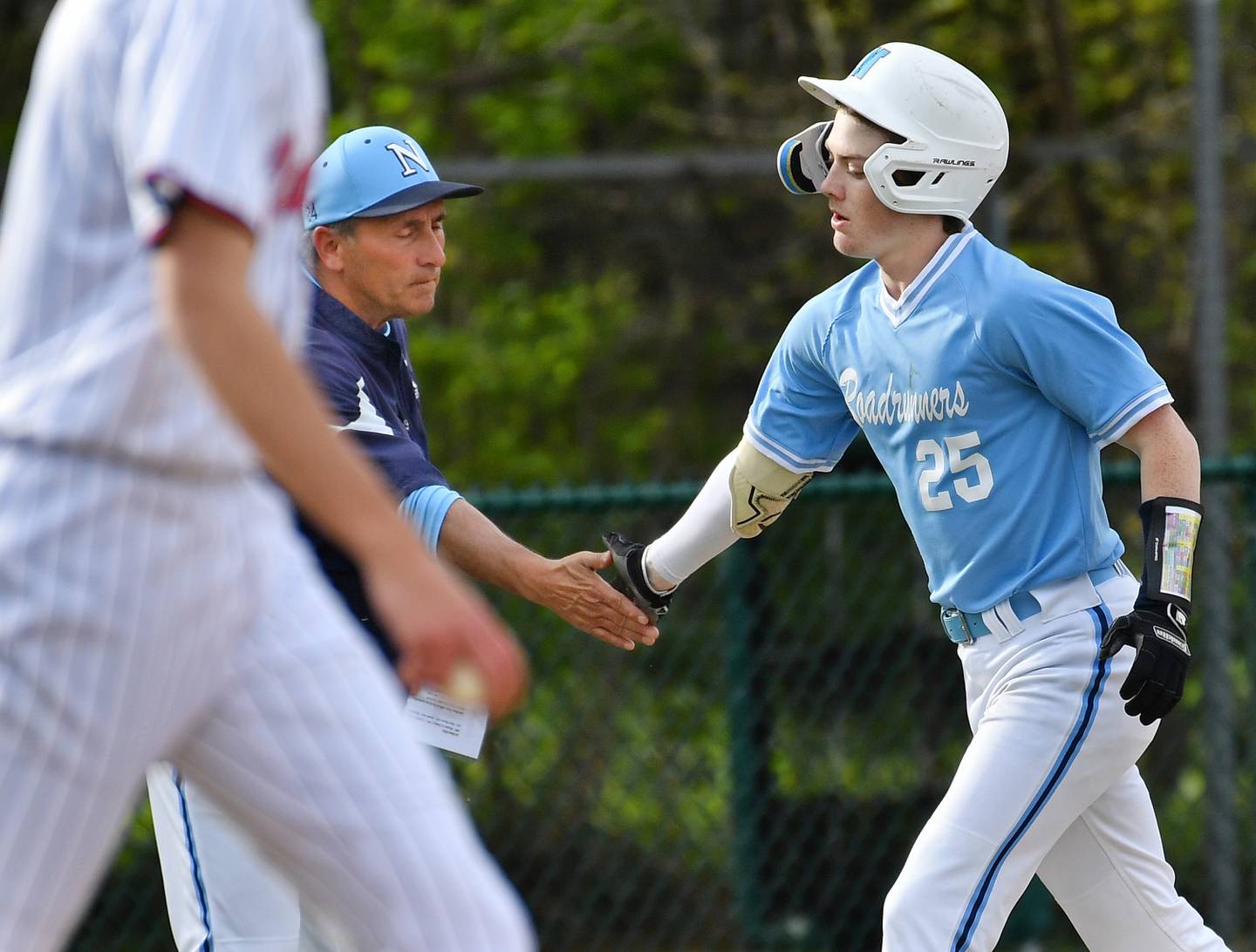 Landon Thome (25) is greeted by Nazareth Academy head baseball coach Lee Milano as he rounds third base after hitting a home run during a game against Benet on April 22, 2024 at Benet Academy in Lisle.