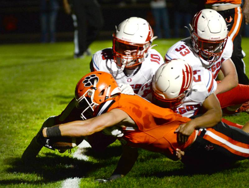 Byron's Brayden Knoll (1) powers his way into the end zone despite the efforts of Oregon's Keaton Salsbury (10), Lucas Cole (24), and Jakob Moser (33) on Friday, Sept. 27, 2024. The Tigers remained undefeated with a 49-7 win over the Hawks.
