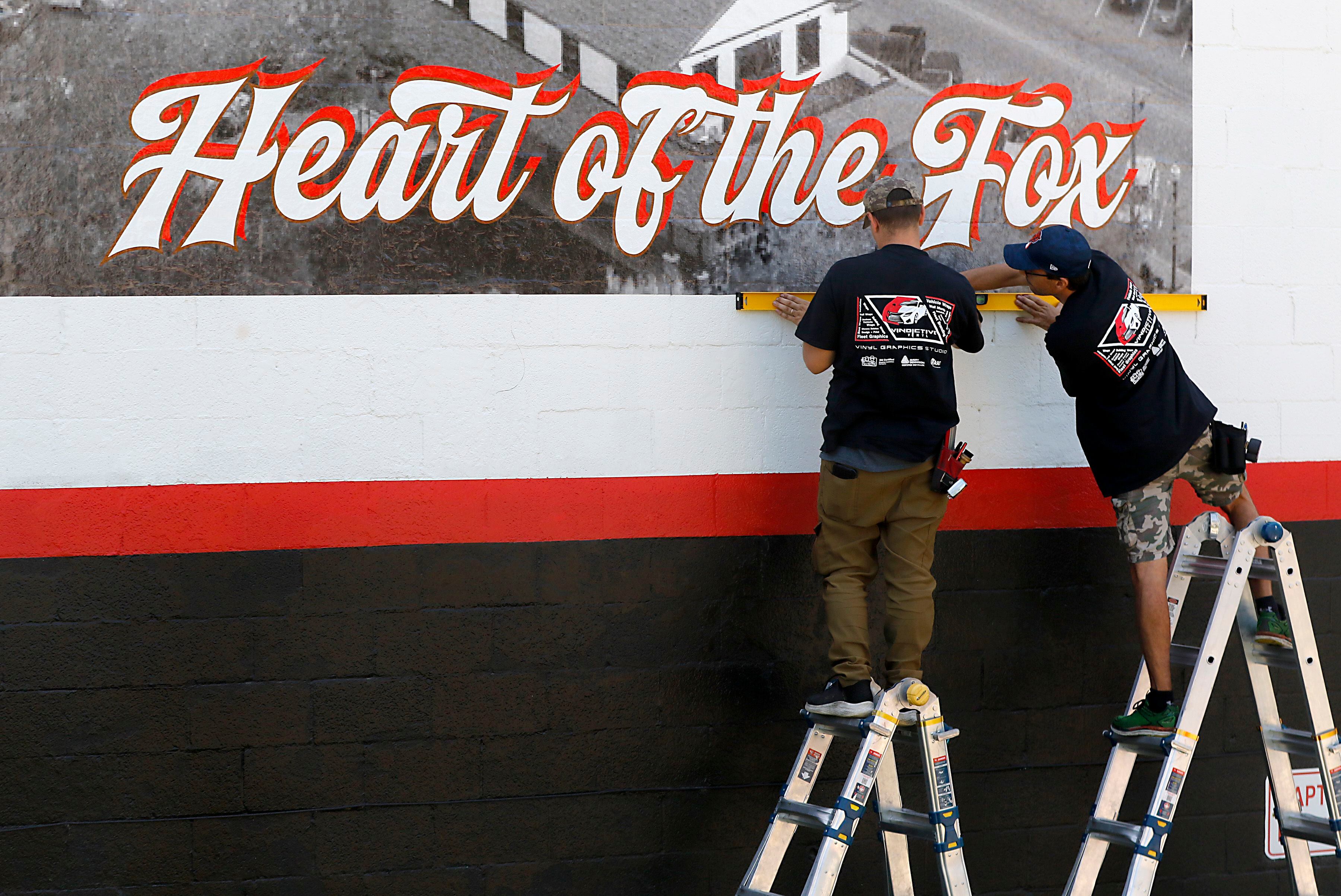 Adam Sciepuk and Chris Szymczuch, of Vindictive Vinyl, work on installing a vinyl mural on Thursday, June 19, 2025, on the side of a building at 3413 W. Elm St, in McHenry. 