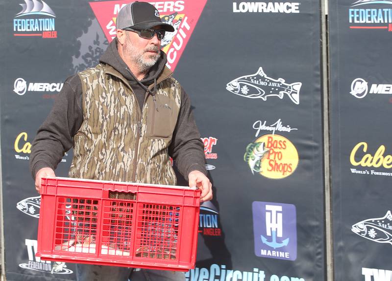 Bill Elliott of Spring Valley, hands his basket of fish to the Illinois Department of Natural Resources that he caught during the annual Masters Walleye Circuit tournament on Friday, March 21, 2025 at the Spring Valley Boat Club.