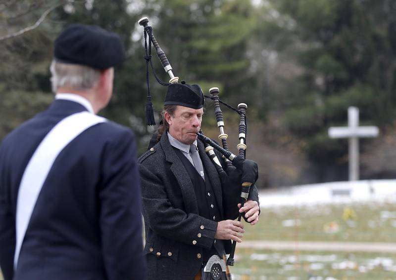 Bob Schafer listens as Tim Hess, of the Dundee Scottish Pipes, plays the bagpipes during the Veterans Day flag placement ceremony Tuesday, Nov. 11, 2025, at the gravesites of veterans at McHenry County Memorial Park Cemetery in Woodstock.