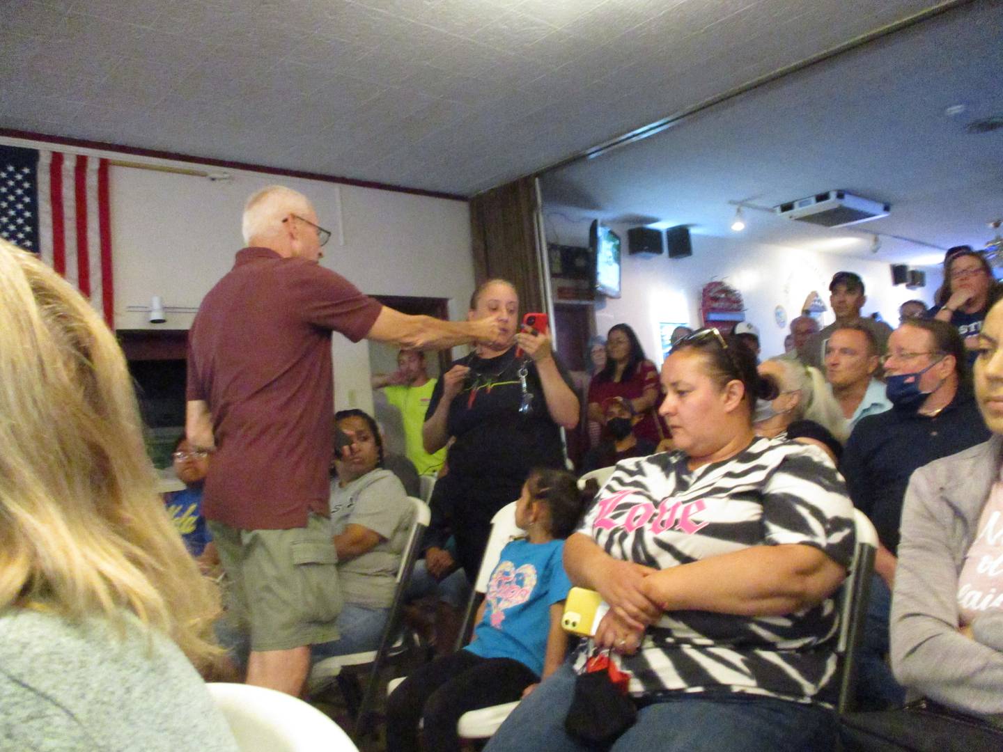 Cunningham Neighborhood Council President John Sheridan passes a microphone around a crowded room during a neighborhood meeting on Wednesday, June 1, 2022 about the Joliet apartment house that has provided residences for five registered sex offenders.