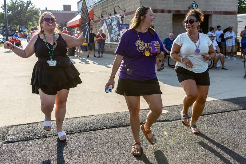 Sara Wright, Katherine Mullen, and Mary Barucci dance to the sounds of 3rd City Brass Band during New Orleans North Festival at Joliet Slammers Stadium on Aug. 15, 2025.