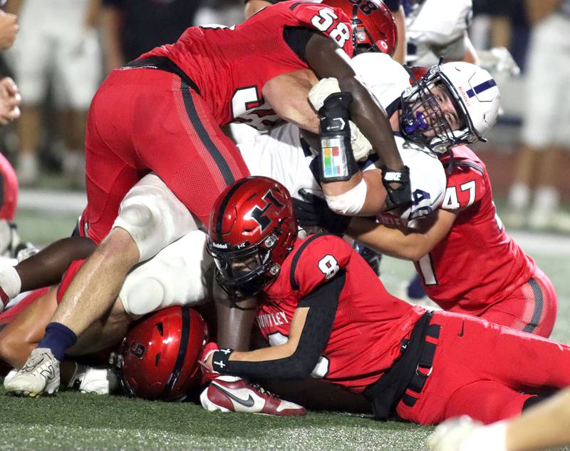 A host of Huntley Red Raiders swarm Cary-Grove’s Logan Abrams in varsity football at Huntley High School in Huntley on Friday, Sept. 19, 2025.