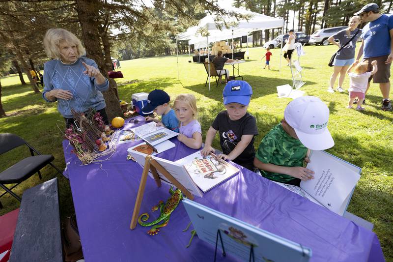 Author Judy Schmidt displays her books to young readers Ben Kilkelly (left), 4, Adele Egli, 3, James Kilkelly, 2, and Sam Kilkelly, 7, Saturday, Sept. 23, 2023 at Lowell Park Schmidt brought in three of her books for the festival.