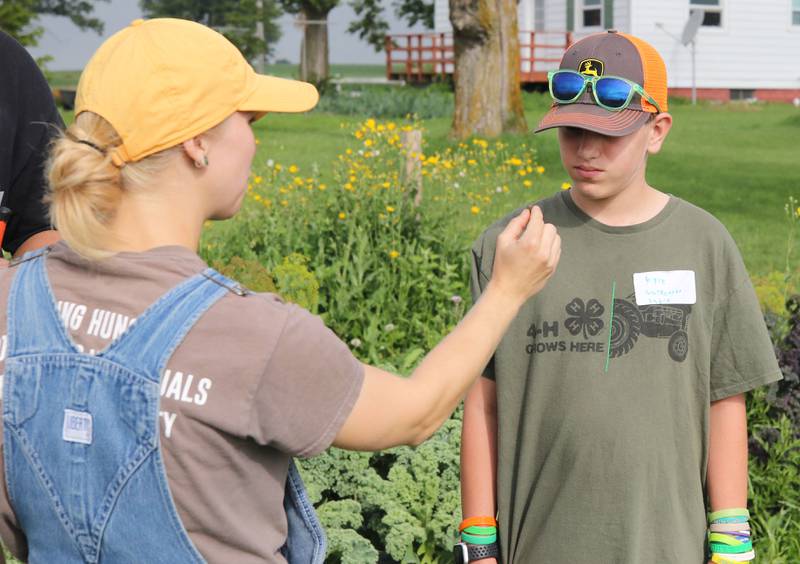 Melina Kuhn, (left) Walnut Grove Vocational Farm program director, shows Kyle Gultnecht-Sabin, 13, an insect Wednesday, July 27, 2022, during the Sustainable Food Safari Camp's stop at Walnut Grove Vocational Farm in Kirkland.