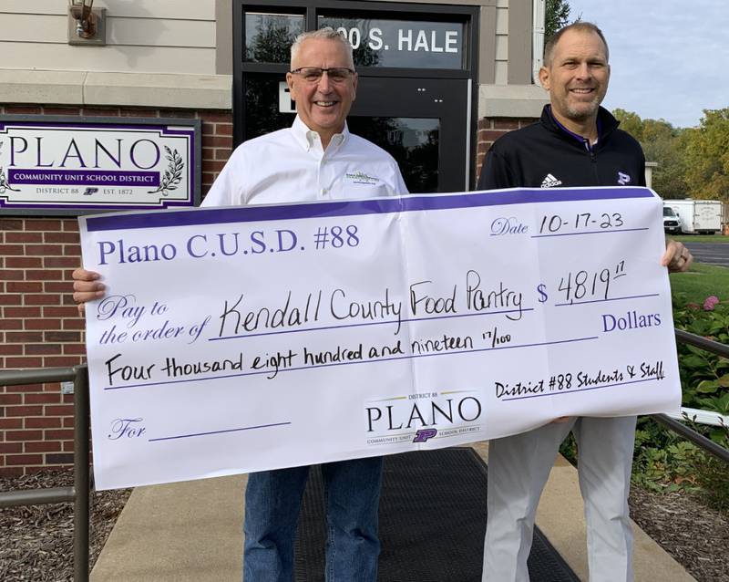 Kendall County Community Food Pantry Board Chair Greg Witek, left, accepts the pantry check from Plano School District 88 Superintendent Tony Baker.