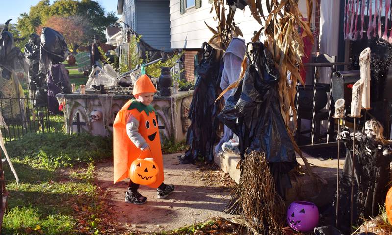 Theodore Martin of DeKalb, 3, dressed as a carrot, receives candy from Lisa Gordon-Ahrens of DeKalb while trick-or-treating on Halloween, Oct. 31, 2021.