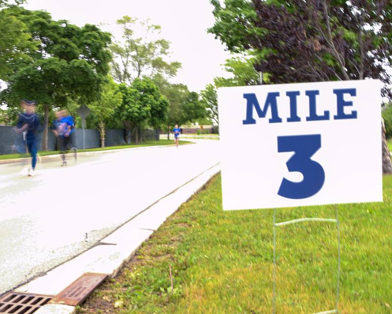 Runners pass the 3 mile sign during the Race to the Flag 5k on Sunday May 25, 2025, held at Ty Warner Park in Westmont.