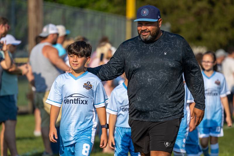 (from left) Parker Valdez walks with father Gorge Valdezat at the opening day ceremony of youth soccer on Saturday, Aug 16, 2025, at Peck Park in Ottawa.