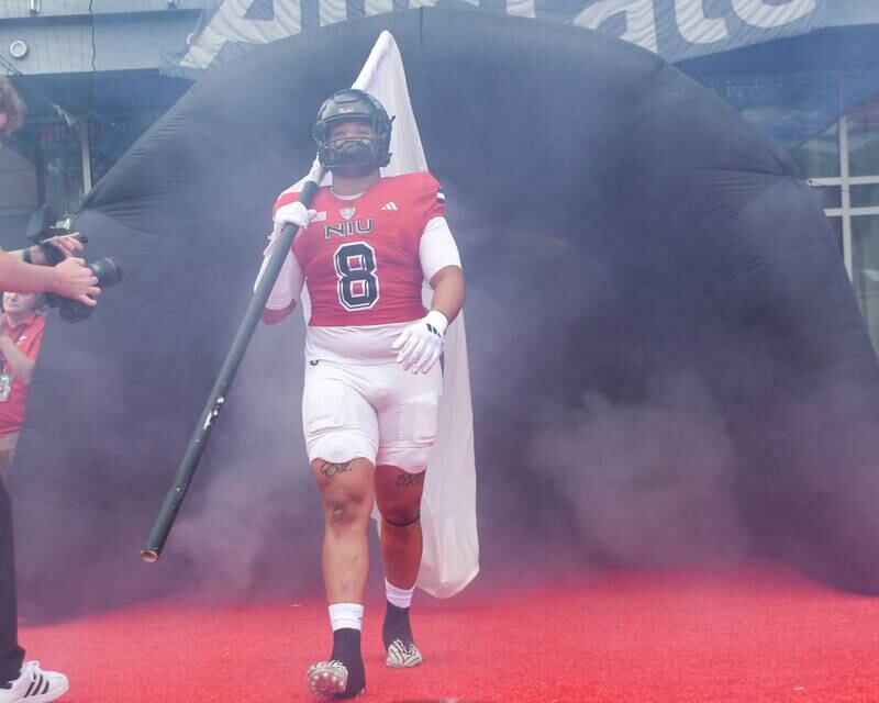 Northern Illinois Huskies defensive tackle Devonte O'Malley (8) comes out onto the field with a flag to run onto the field for the Saturday Sept. 21, 2024, game while taking on Buffalo at Huskie Stadium in DeKalb.
