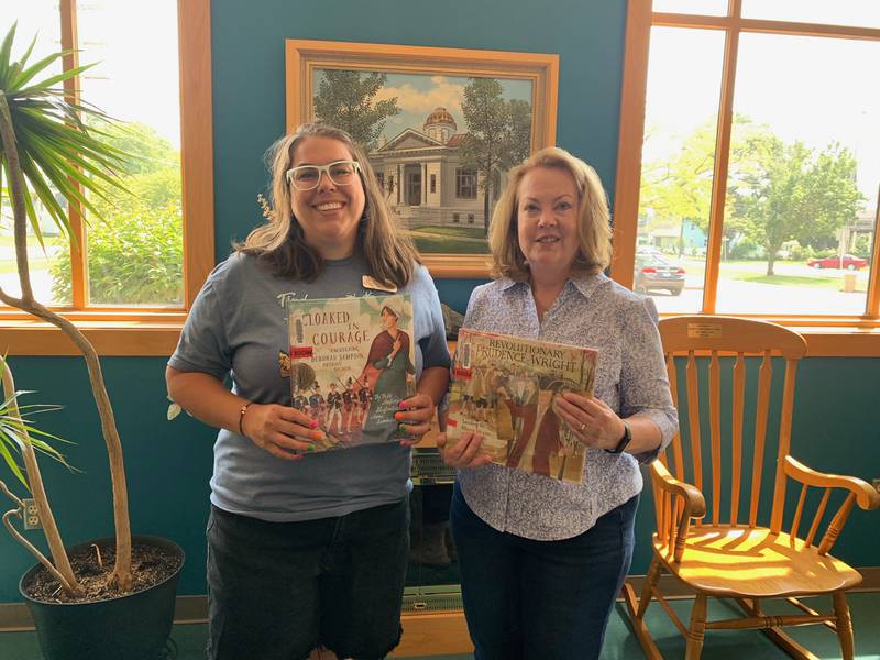 Emily Kofoid, Graves Hume Library director, and Beverly Richardson, co-chair of the DAR 250 grant program, pose for a photo with children's books purchased for five local libraries, including Graves Hume in Mendota.