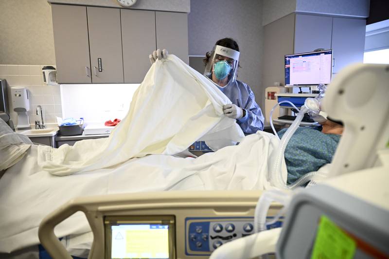 FILE - In this Monday, Dec. 7, 2020 file phto, Marie Pelkey, a critical care nurse at North Memorial Health Hospital in Robbinsdale, Minn., drapes a warm blanket over a COVID-19 patient who was just admitted into the South Seven Intensive Care Unit after their condition worsened.