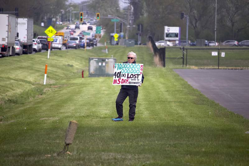 Luane Randolph holds up a sign on Thursday, May 1, 2025, for a democracy rally in Joliet with signs critical of U.S. President Donald Trump. More than 20 people attended the rally that was held near the busy West Jefferson Street and the Joliet Regional Airport.