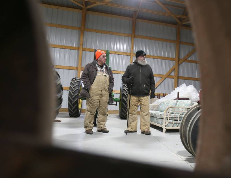 Jim Clinton of LaMoille and Joe Carpenter of Ohio, browse through different tractors during the Pat and Sharon Broeren auction on Saturday, Dec. 13, 2025 at Dahl Real Estate Auctions and Appraisals in Walnut. The tractor was made in the 1930's and was the oldest one of the Broeren's collection.
