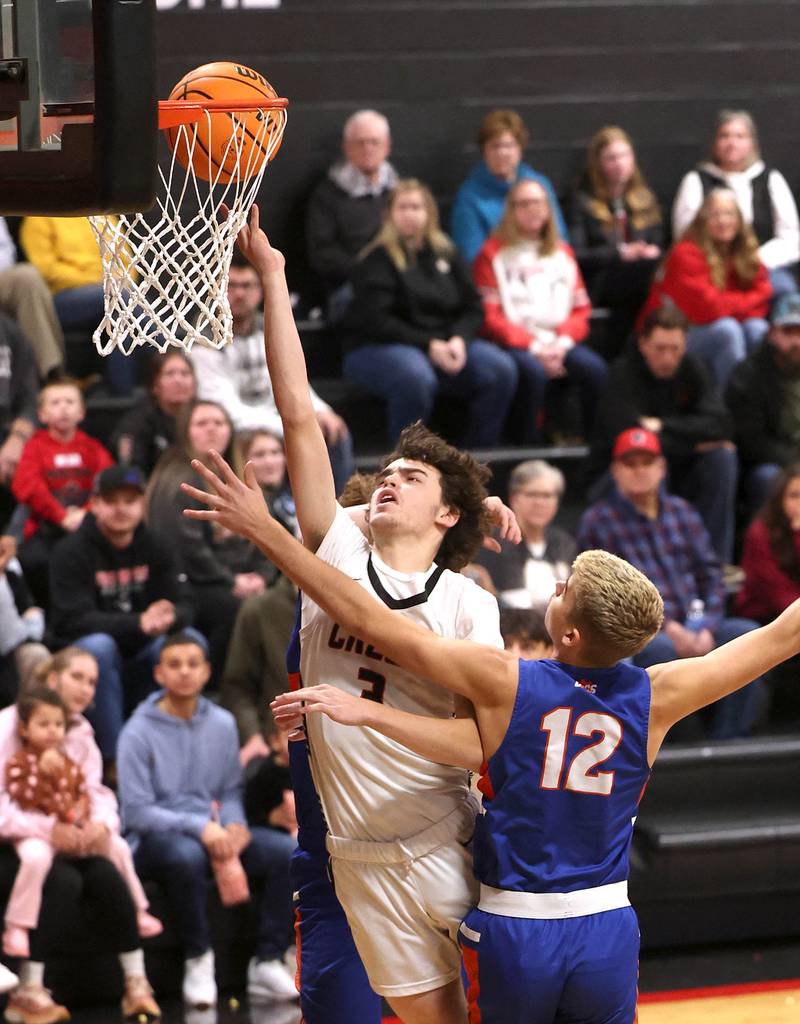 Indian Creek's Logan Schrader gets a layup over Genoa-Kingston's John Swineheart during their game Friday, Jan. 3, 2025, at Indian Creek High School in Shabbona.