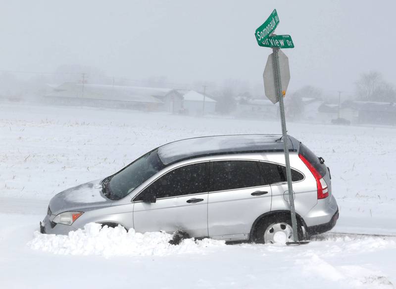 A vehicle sits in the ditch against the street sign Monday, March 16, 2026, at the corner of Somonauk Road and Fairview Drive in Cortland. A March snowfall covered DeKalb County in about six inches of the white stuff Sunday night into Monday.