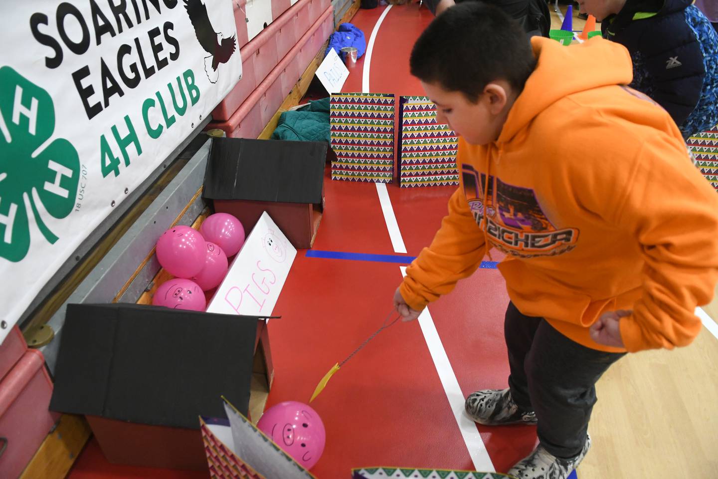 Connor Clark, 8, of Rochelle herds a balloon pig into its pen with a fly swatter at the Leaf River Soaring Eagles' booth at the 4-H Penny Carnival on Saturday, March 18.