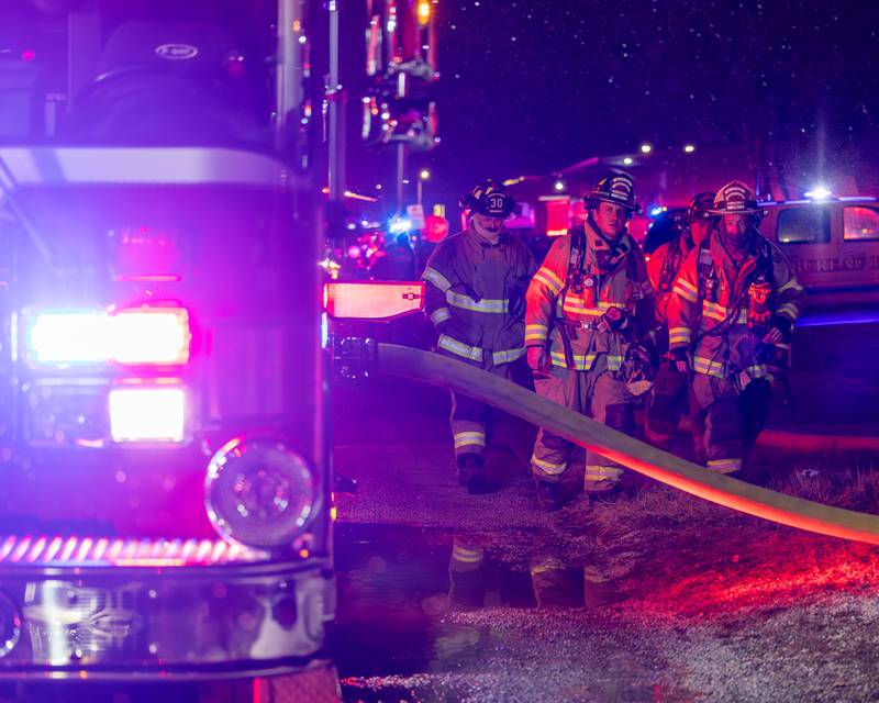 Firefighters standing outside front door of a '2nd Alarm' house fire point towards flame on Saturday, January 10, 2026, at 217 West Delvin Street in Spring Valley.