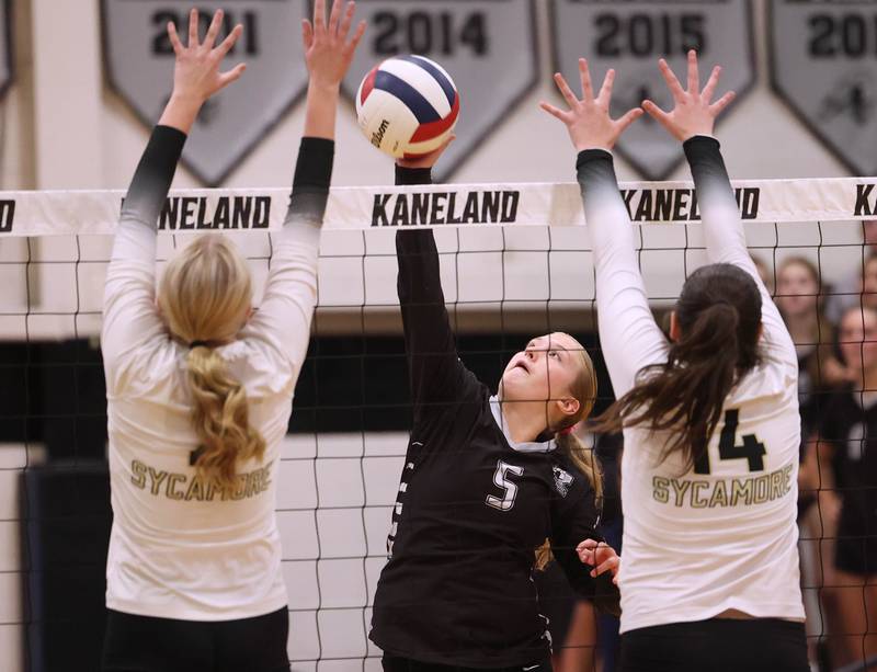 Kaneland's Abigail Carter tries to spike the ball between two Sycamore blockers during their match Tuesday, Sept. 30, 2025, at Kaneland High School in Maple Park.