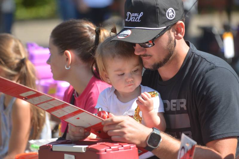 Blayke Dean, 1, of Rock Falls, checks out her trophy as her dad, Tanner, checks out the new fishing gear she won at the Whiteside County Sheriff Office and Mounted Patrol's annual fishing derby at Morrison-Rockwood State Park in Morrison on Saturday, Sept. 9, 2023.
