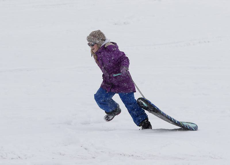Zuzia Hay, 10, runs up the hill after making a sledding run Wednesday, Jan. 25, 2023, at Veteran Acres Park in Crystal Lake. Snow fell throughout the morning, leaving a fresh blanket of snow in McHenry County.